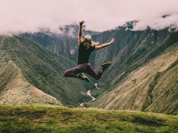 Photo d'une femme sautant de joie face à un magnifique paysage montagneux