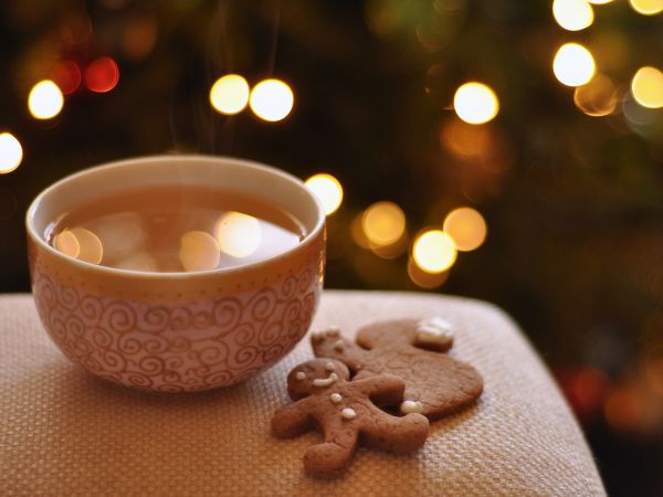 Photo d'un bol de tisane avec un petit biscuit d'homme en pain d'épices et des lumières chaleureuses