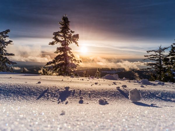 Photo d'un soleil à l'horizon dans un paysage montagneux enneigé