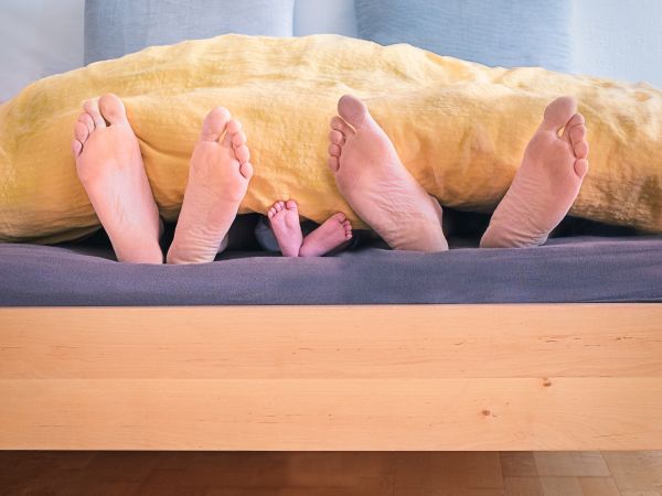 Trois paires de pieds qui dépassent d'un lit