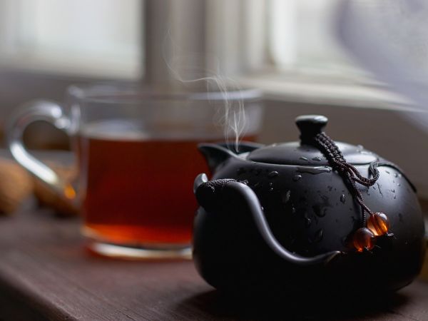 Une théière japonaise noire fumante et une tasse de thé
