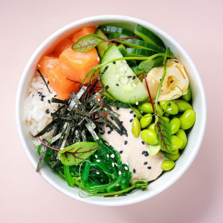 Photo d'un pokébowl contenant du saumon, des fèves, des algues nori, du concombre, du riz, du houmous, et quelques herbes...